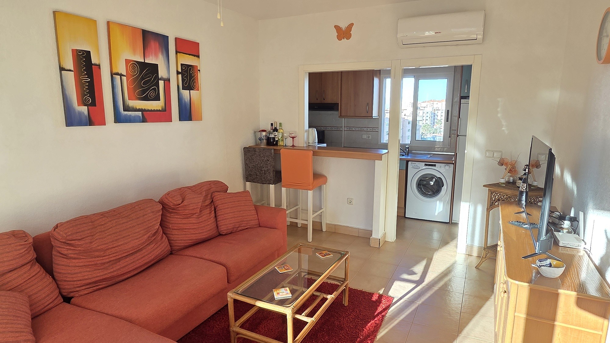 Salón con sofá, mesa baja y barra abierta a la cocina