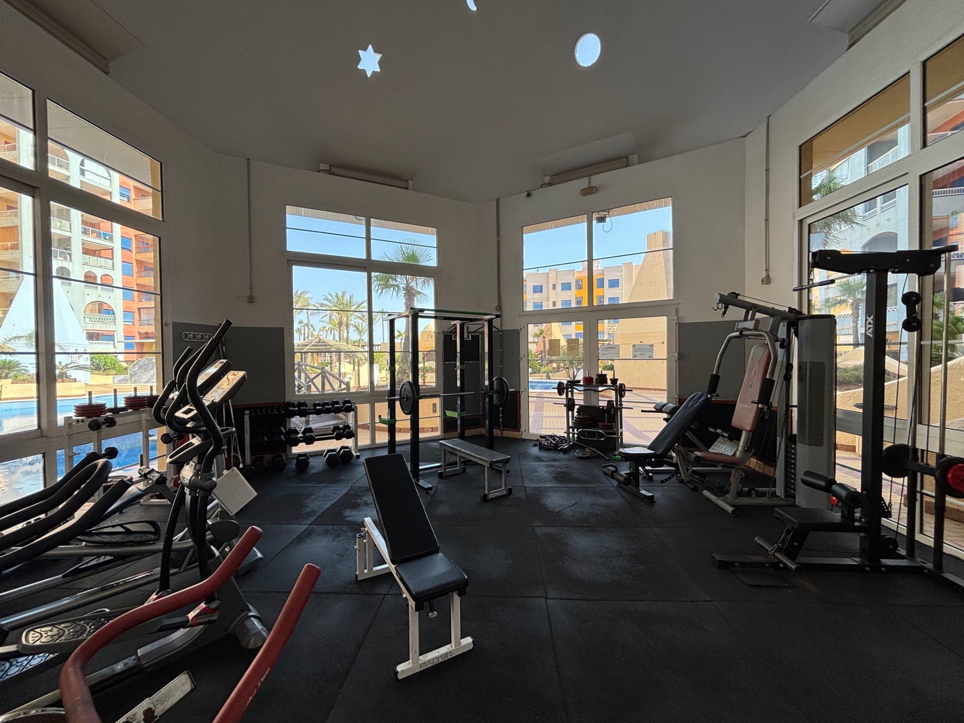Gimnasio de la urbanización con máquinas y grandes ventanales