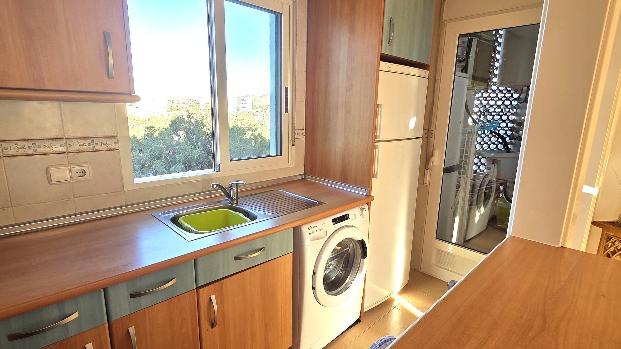 Cocina con fregadero, encimera y lavadora bajo la encimera