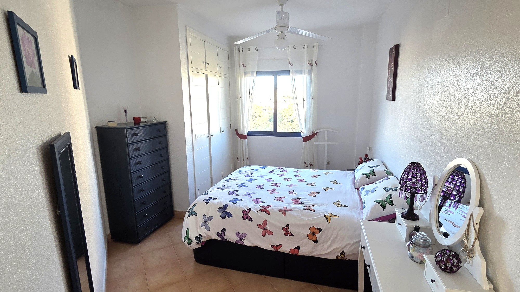 Dormitorio con ventana amplia, cómoda y ventilador de techo