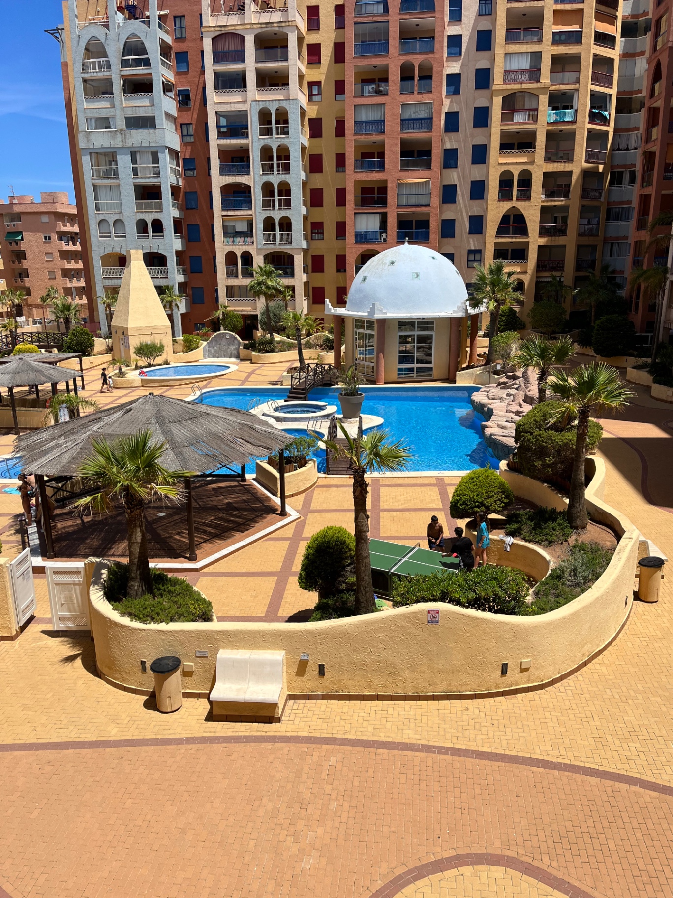 Piscina comunitaria de la urbanización con palmeras y puente