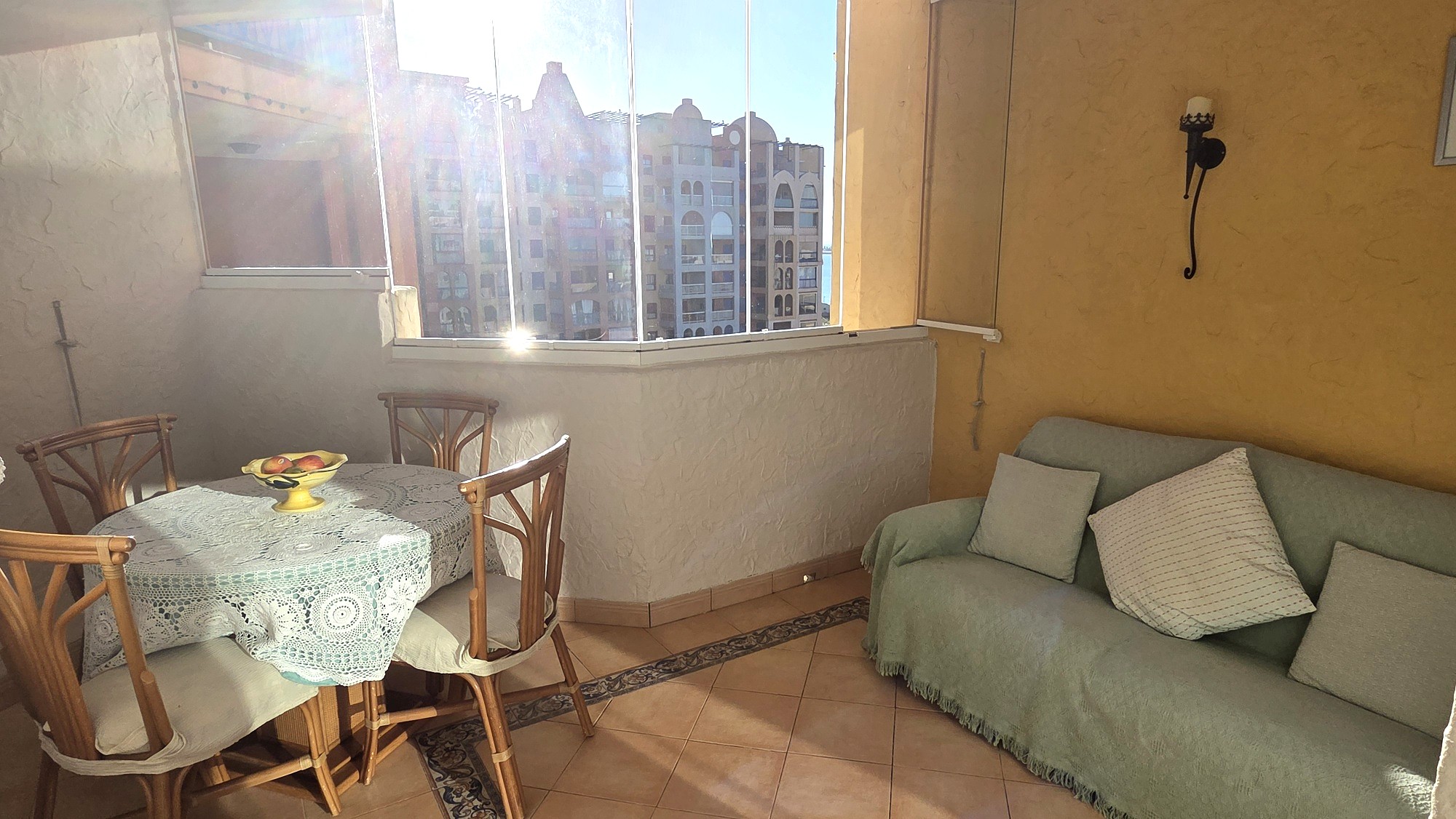 Zona acristalada con sofá, mesa y mucha luz natural